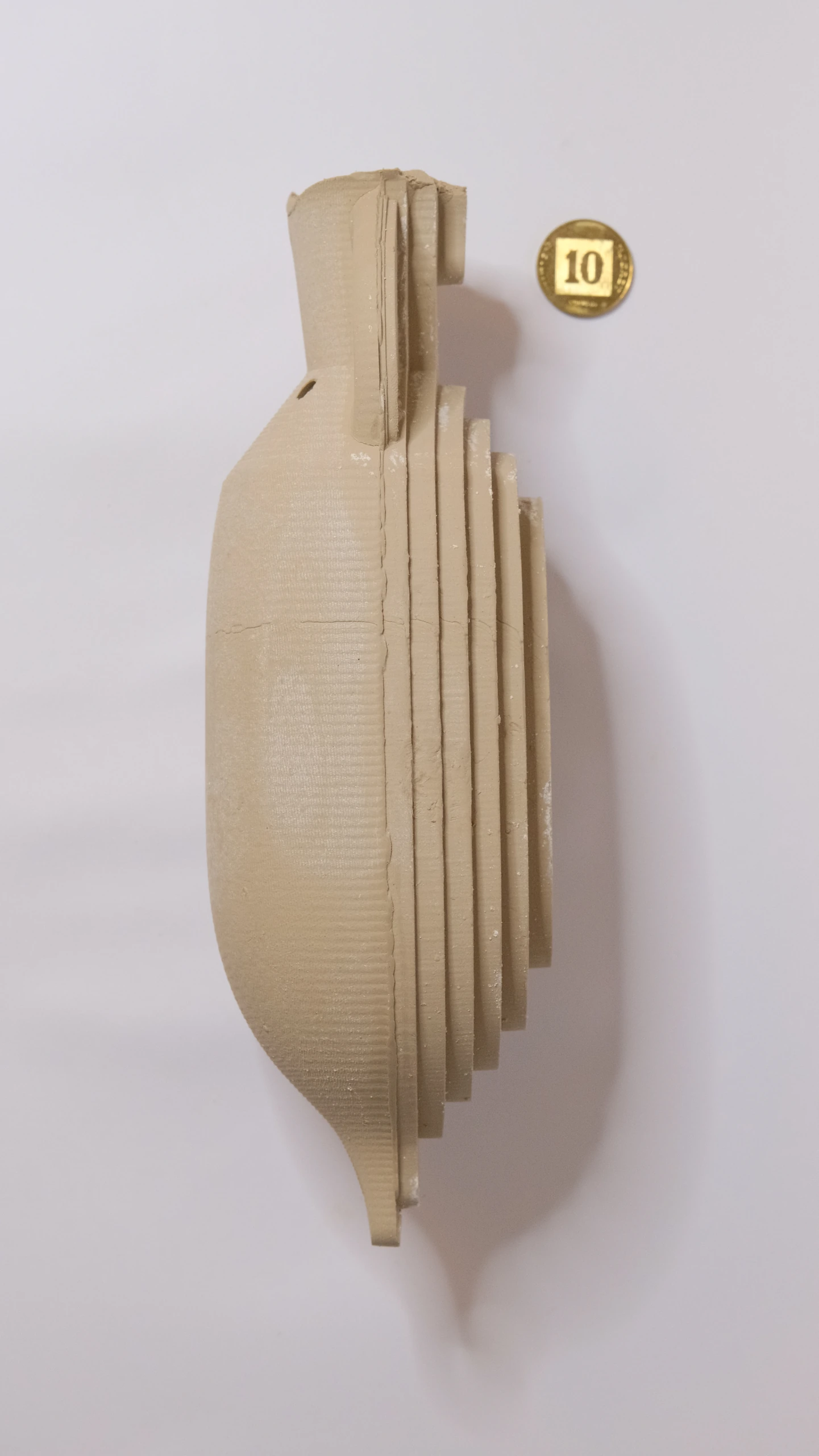 Side profile of the large clay Amphora, with fine curves on the left and coarse layers on the right